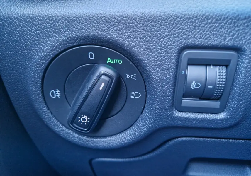 Gros plan sur les commandes d’éclairage noir mat du tableau de bord d’une Skoda Fabia blanche de 2022.