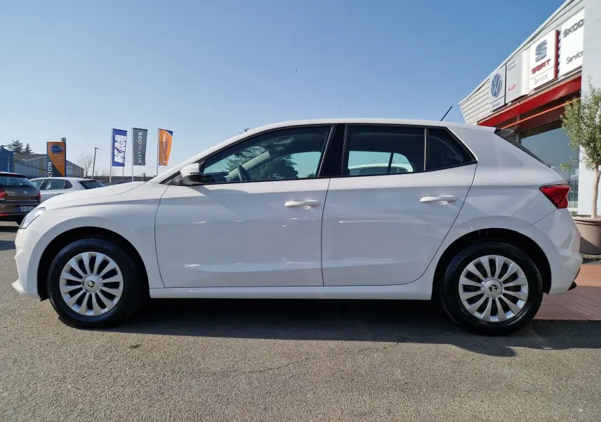 Vue de profil côté gauche d'une Skoda Fabia berline blanche 2022 avec jantes alliage et vitres teintées.