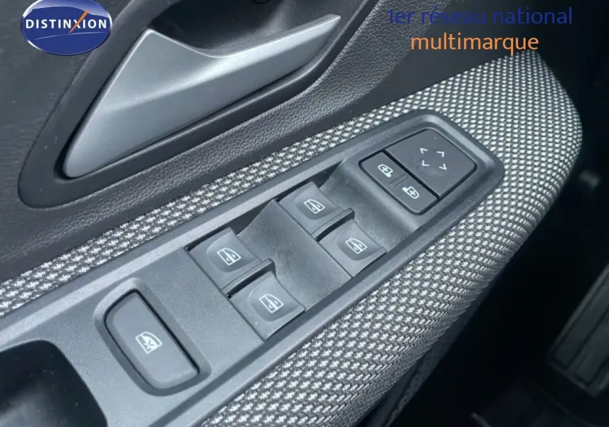 Gros plan sur les commandes des vitres électriques et rétroviseurs côté conducteur, garniture tissu gris.