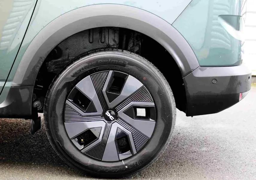 Gros plan sur la roue arrière droite du Dacia Jogger vert cèdre métal, avec jante au design géométrique moderne.