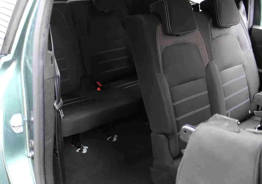 Vue intérieure arrière droite du Dacia Jogger vert cèdre, montrant les sièges en tissu noir avec surpiqûres claires.