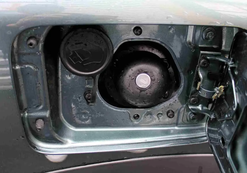 Gros plan sur la trappe à carburant ouverte du Dacia Jogger vert cèdre métal, montrant les bouchons essence et GPL.