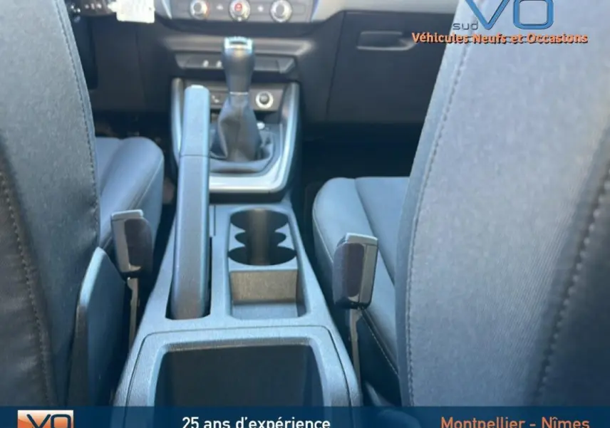 Vue intérieure centrée sur la console centrale et levier de vitesses manuelle de l'Audi A1 Sportback gris foncé.