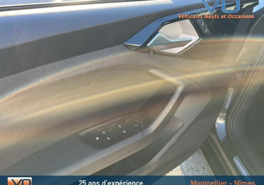 Vue intérieure côté gauche de la porte avant gris foncé de l'Audi A1 Sportback avec commandes des vitres électriques.