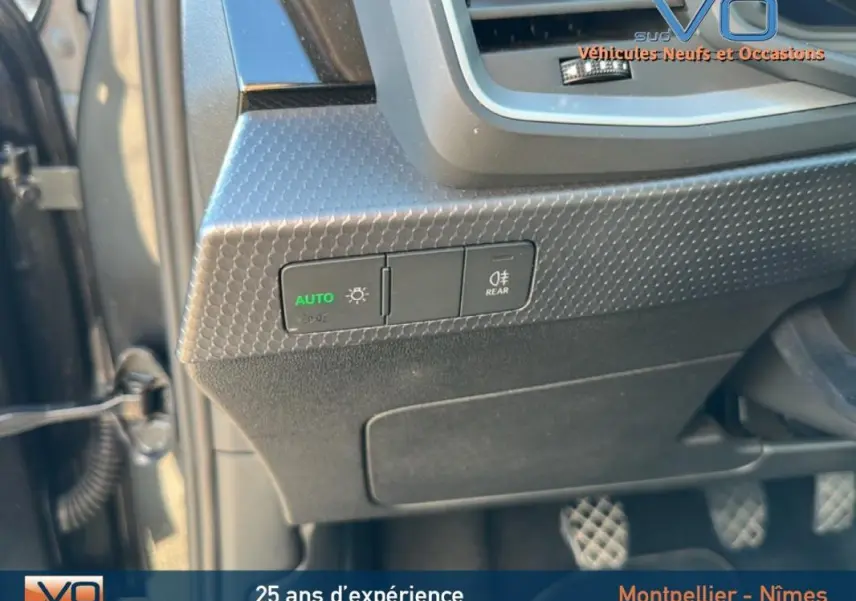 Gros plan sur les commandes d’éclairage à gauche du volant d’une Audi A1 Sportback gris foncé, version 2019.