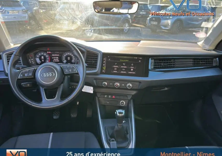 Vue intérieure de face de l'Audi A1 Sportback gris foncé, volant cuir, tableau de bord avec écran tactile et boîte manuelle.