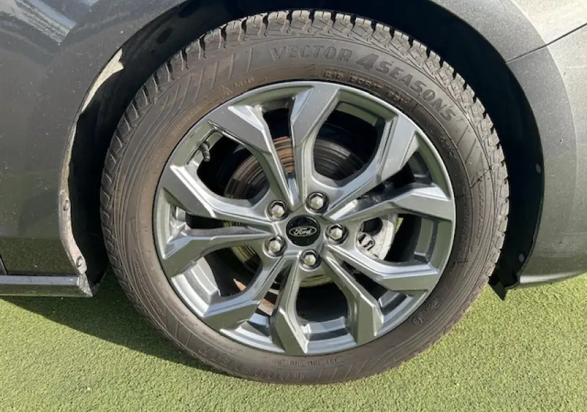 Gros plan sur la roue avant droite de la Ford Focus IV gris magnetic avec jante alliage 17 pouces à 5 branches.