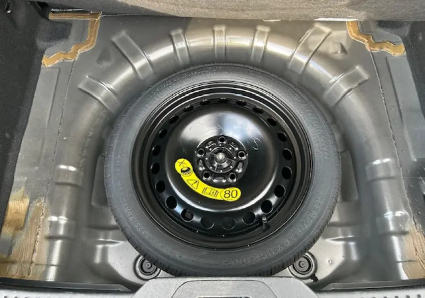 Vue plongeante sur la roue de secours galette noire dans le coffre de la Ford Focus IV gris Magnetic Metal.