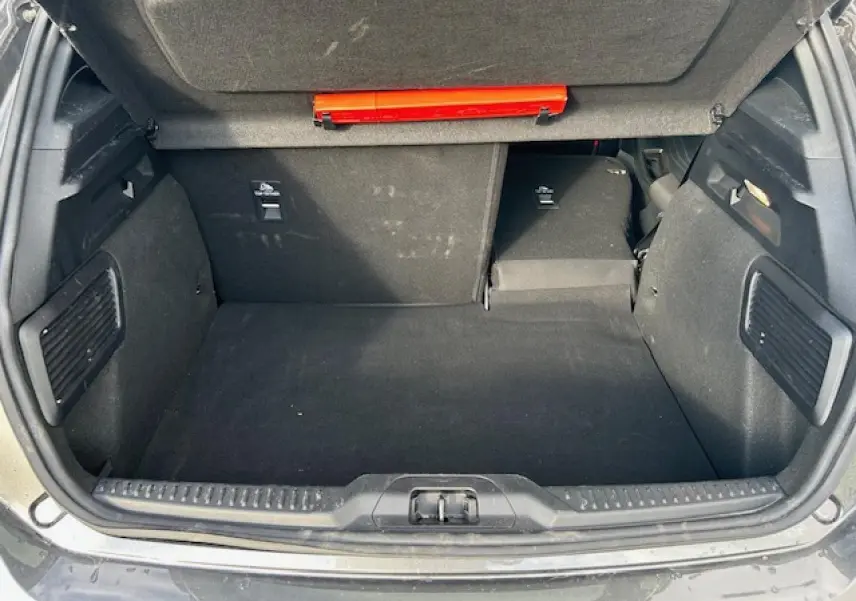 Coffre ouvert vu de l'arrière de la Ford Focus IV gris Magnetic, banquette arrière rabattue partiellement côté droit.