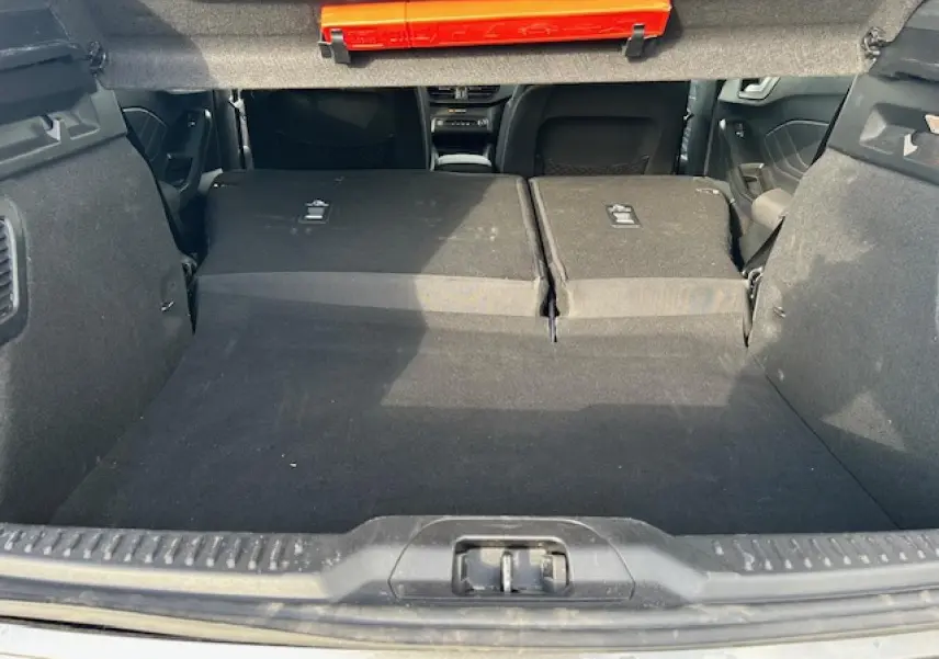 Coffre ouvert vu de l'arrière avec banquette arrière rabattue, intérieur noir d'une Ford Focus IV gris Magnetic Metal.