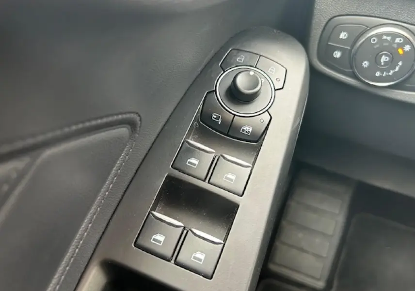 Gros plan sur les commandes des vitres et rétroviseurs côté gauche de la Ford Focus IV ST-Line X gris Magnetic Metal.