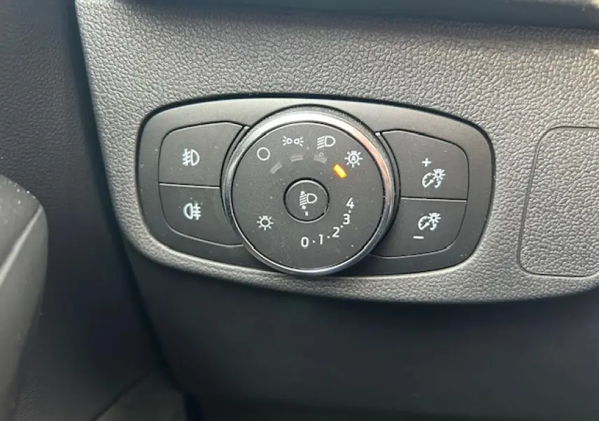 Gros plan sur le bouton de réglage des phares et feux antibrouillard dans l’habitacle d’une Ford Focus gris magnetic.