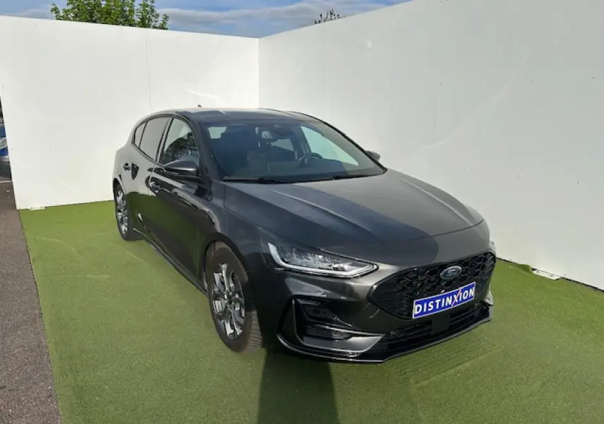 Ford Focus IV ST-Line X gris métallisé vue 3/4 avant avec calandre noire et jantes alliage 17 pouces.