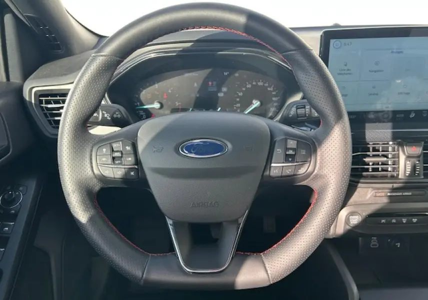 Vue intérieure frontale du volant ST-Line noir avec surpiqûres rouges et combiné numérique de la Ford Focus IV gris Magnetic Metal.