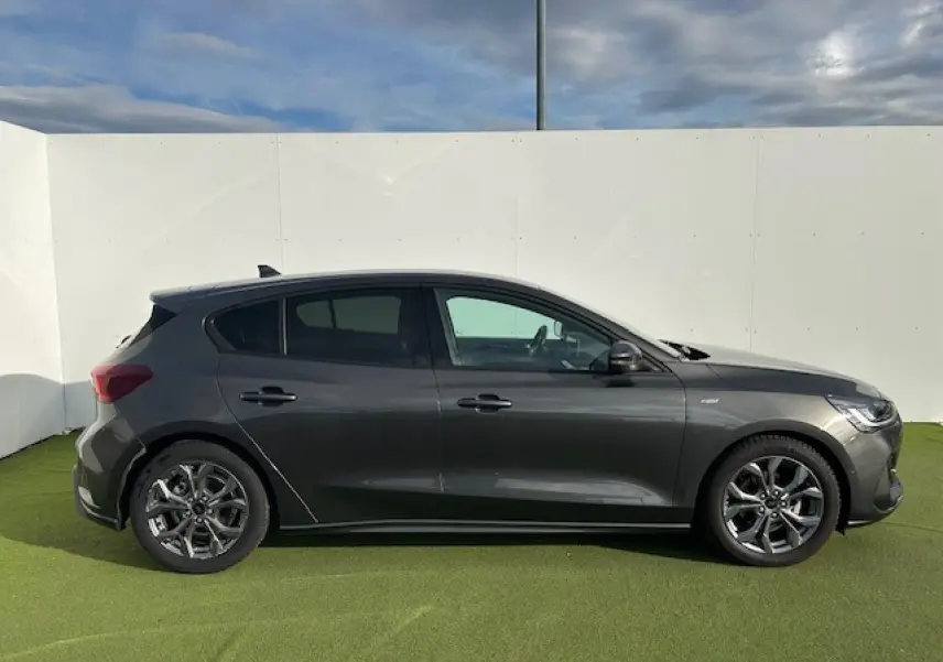 Ford Focus IV ST-Line X gris métallique vue de profil côté gauche sur fond clair avec jantes alliage 17 pouces.