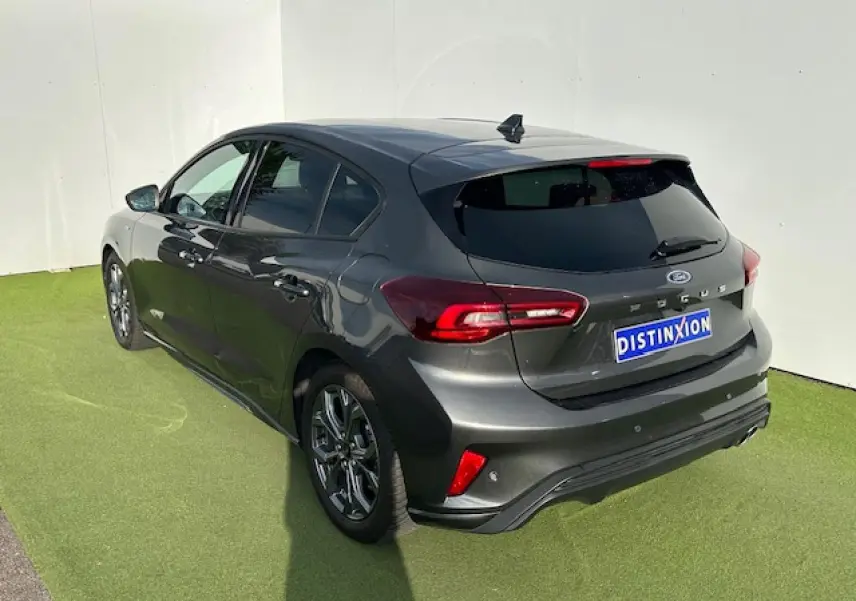 Vue 3/4 arrière droite d'une Ford Focus IV ST-Line X gris magnetic métallisé avec jantes alliage et double sortie d'échappement.