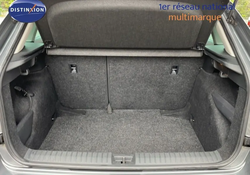 Coffre ouvert d’un Skoda Kamiq gris graphite métal, vue arrière montrant l’espace de chargement vide et revêtement tissu gris.