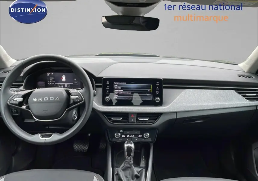 Vue frontale de l'intérieur du Skoda Kamiq 2025 gris graphite, avec tableau de bord moderne et écran tactile central.