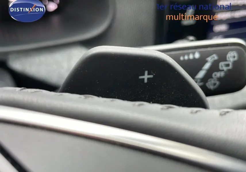 Détail du levier de commande + au volant cuir du Skoda Kamiq gris graphite, avec commandes d’essuie-glace en arrière-plan flou.