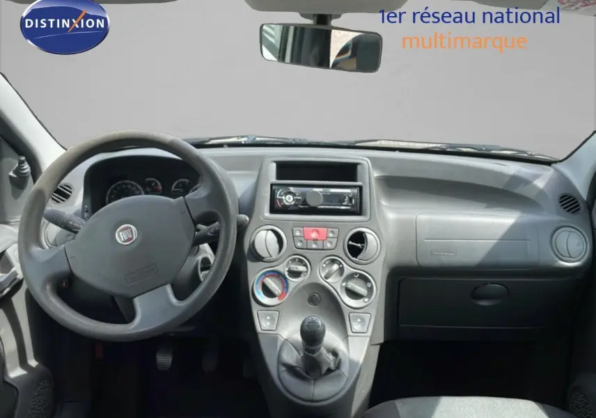 Vue frontale de l'habitacle de la Fiat Panda blanche, mettant en valeur le tableau de bord et la boîte manuelle.