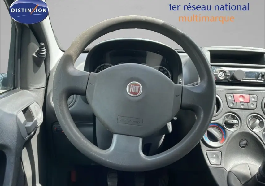 Vue intérieure centrée sur le volant gris de la Fiat Panda blanche, avec tableau de bord et commandes visibles.