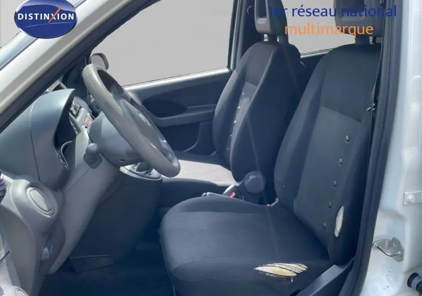 Vue intérieure côté conducteur d'une Fiat Panda blanche de 2011, sièges noirs usés avec déchirures visibles.