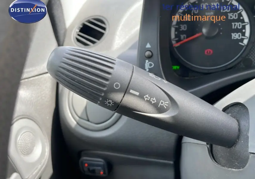 Gros plan sur la commande des feux et clignotants à gauche du volant dans l’habitacle d’une Fiat Panda blanche de 2011.