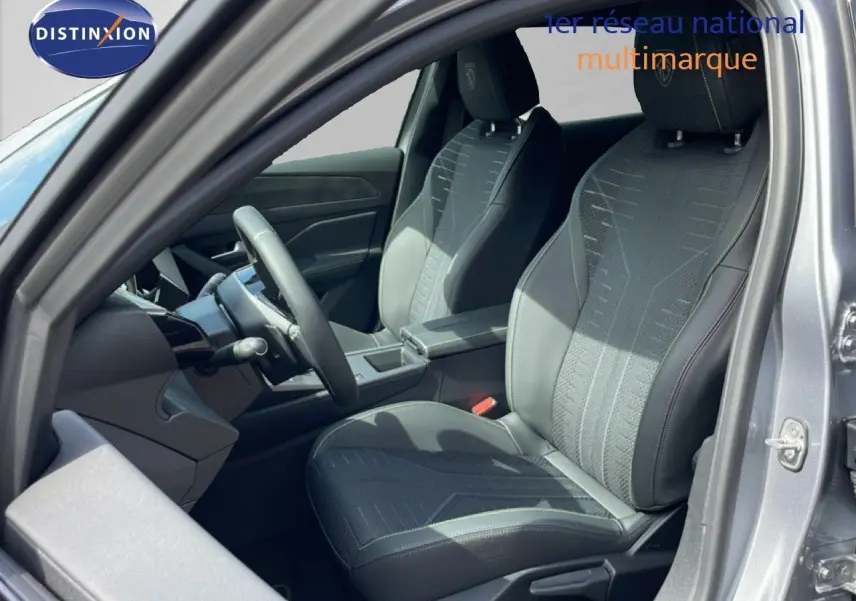 Vue intérieure côté conducteur de la Peugeot 308 gris Artense, sièges tissu et cuir noir avec volant multifonction.