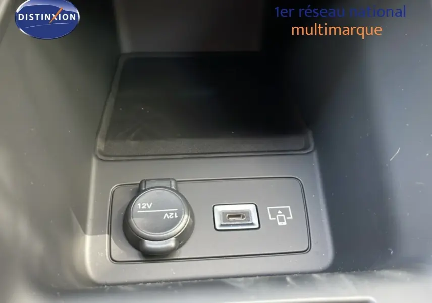 Prise 12V et port USB-C en gros plan dans la console centrale d'une Peugeot 308 gris Artense hybride 2026.