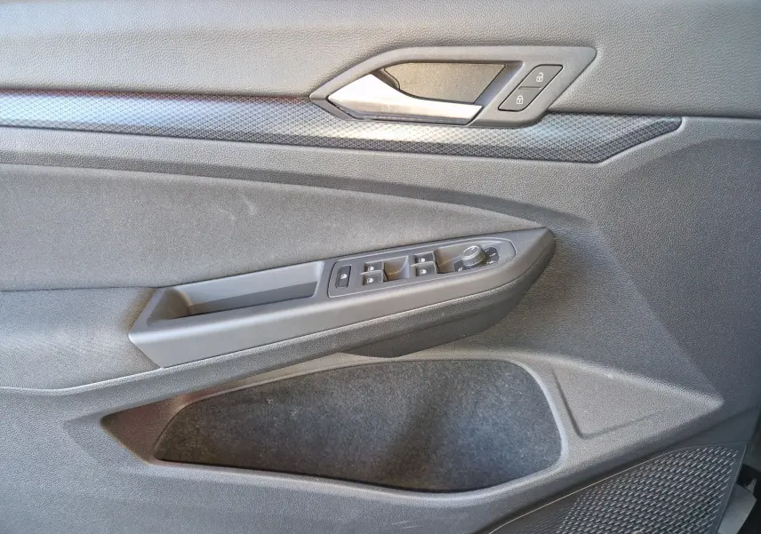 Intérieur de la porte côté gauche de la Volkswagen Golf VIII noire, avec commandes de vitres et verrouillage visibles.