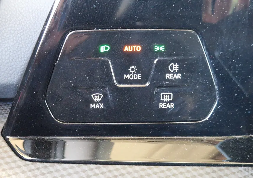 Panneau de commandes d'éclairage et désembuage de la Volkswagen Golf VIII noir métal, avec voyants verts et orange allumés.