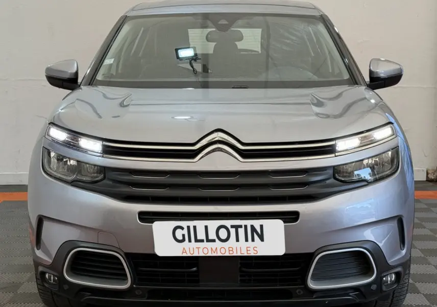 Vue frontale d'un Citroën C5 Aircross gris clair avec feux LED allumés et calandre noire distinctive.
