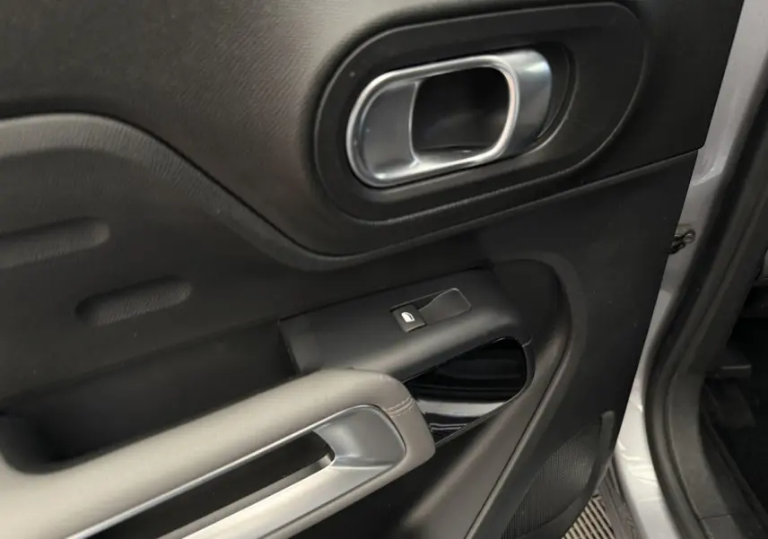 Détail de la porte avant gauche gris clair du Citroën C5 Aircross avec poignée argentée et commande de vitre électrique.