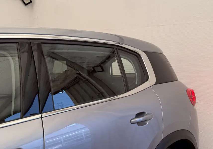 Vue latérale arrière côté droit du Citroën C5 Aircross gris clair avec contours de fenêtres chromés et feux arrière rouges.