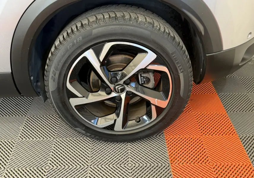 Gros plan sur la roue avant droite d'un Citroën C5 Aircross gris clair avec jante alliage noire et argentée.
