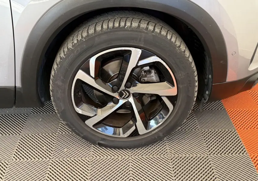 Gros plan sur la roue avant droite d’un Citroën C5 Aircross gris clair avec jante alliage bicolore moderne.