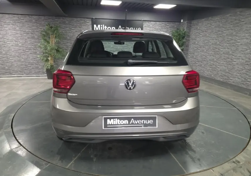 Vue arrière d'une Volkswagen Polo gris métallisé 2020 avec feux rouges et logo VW visible, stationnée en intérieur.