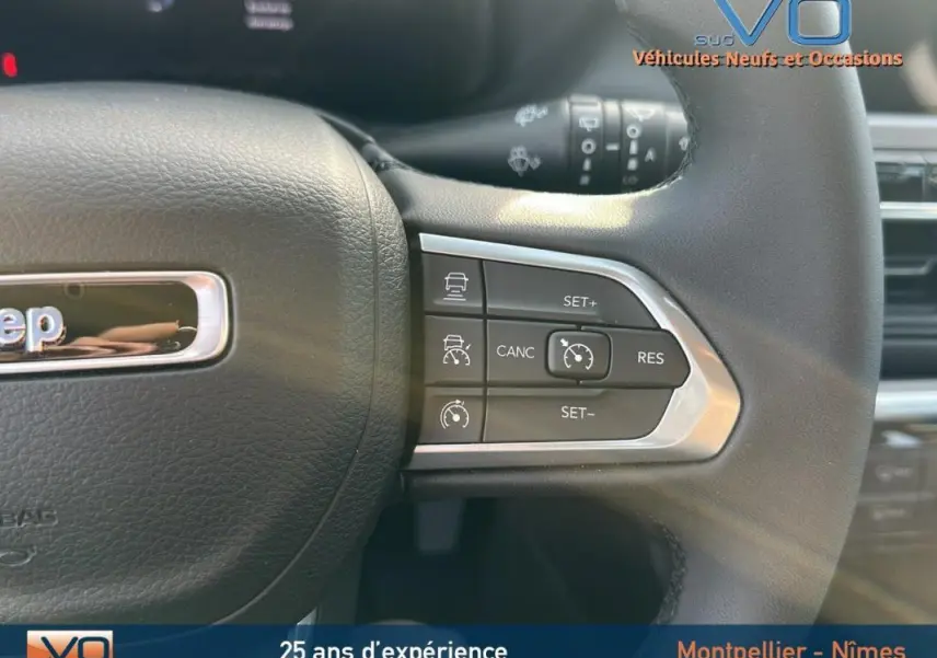 Gros plan sur le volant noir du Jeep Compass 2024 avec commandes de régulateur de vitesse intégrées.