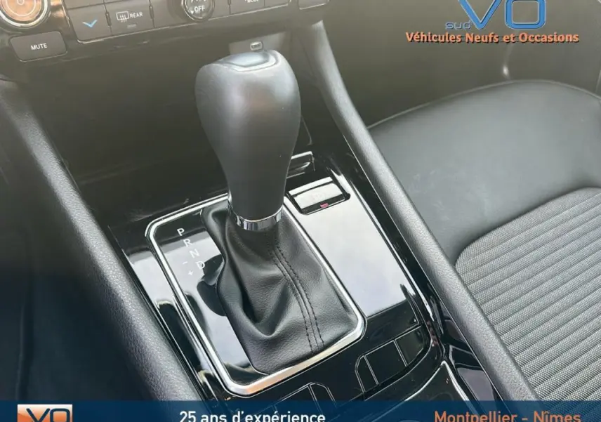 Gros plan sur la console centrale noire du Jeep Compass 2024, mettant en valeur le levier de vitesse automatique et l'accoudoir.