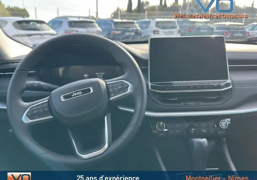 Vue intérieure centrée sur le volant Jeep noir et l'écran tactile du tableau de bord du Compass 2024.