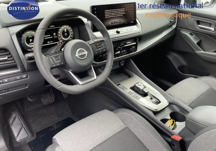 Intérieur du Nissan Qashqai 1.5 E-POWER 2026, vue côté conducteur montrant le tableau de bord et la console centrale gris et noir.