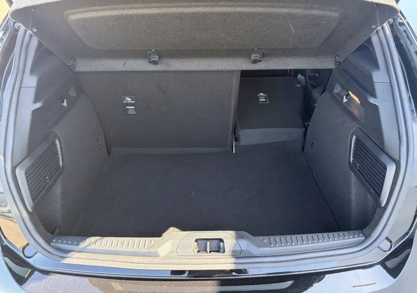 Coffre ouvert vu de l'arrière d'une Ford Focus IV noire avec banquette arrière partiellement rabattue.