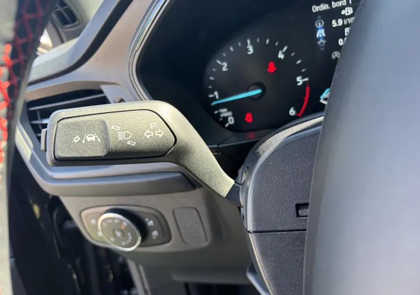 Gros plan sur la manette de clignotants à gauche du volant noir avec tableau de bord numérique de la Ford Focus IV ST-Line.