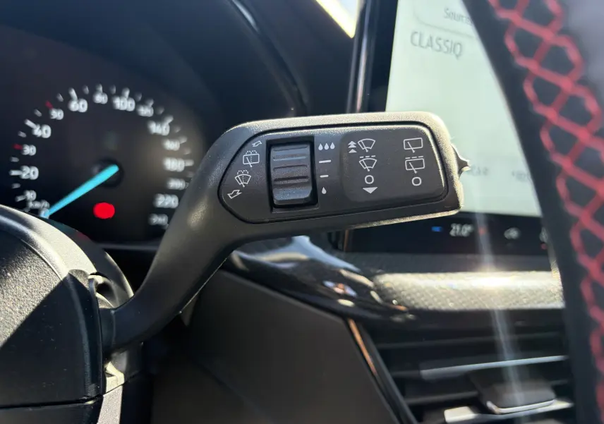Gros plan sur la commande des essuie-glaces dans l'habitacle noir avec surpiqûres rouges de la Ford Focus IV ST-Line X.
