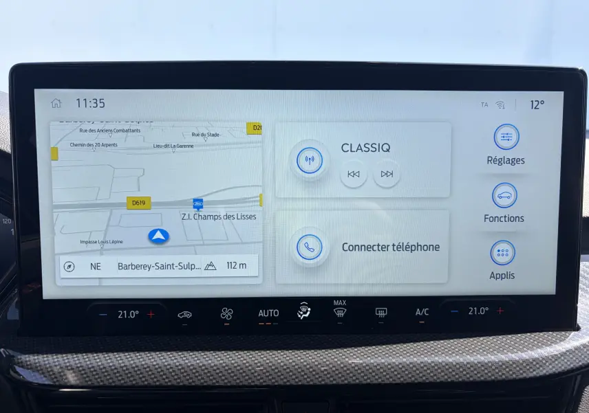 Écran tactile central de la Ford Focus IV noire, affichant navigation, radio et commandes climatisation.
