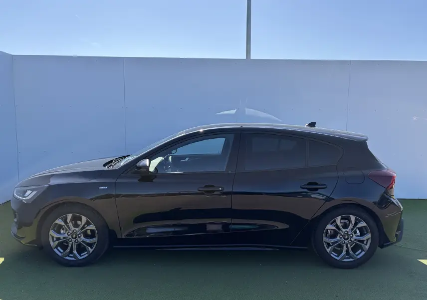 Profil droit d'une Ford Focus IV ST-Line X noire Agate avec jantes alliage 17 pouces et vitres surteintées.