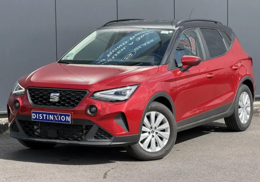 SEAT Arona Rouge Désir en 3/4 avant droit, toit noir contrasté et jantes alliage 16 pouces visibles.