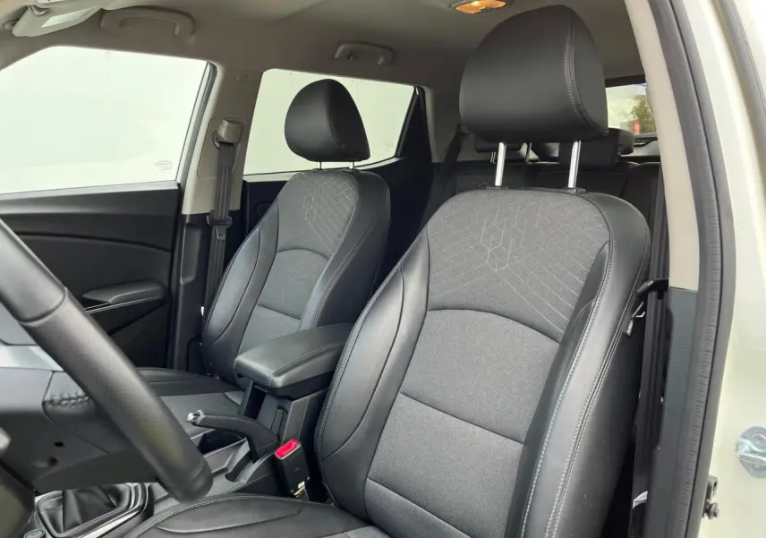 Vue intérieure côté conducteur du SSANGYONG TIVOLI 2021, sièges tissu et cuir noir avec surpiqûres grises.