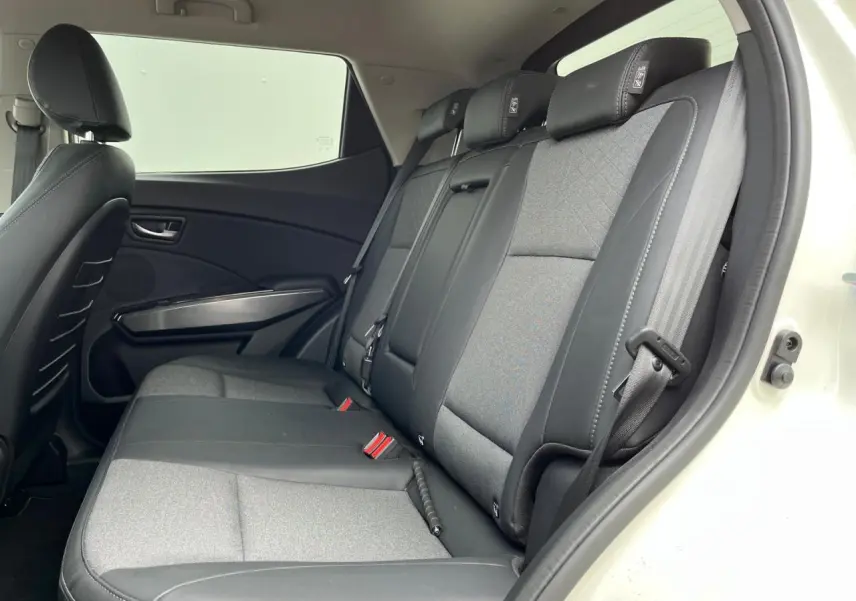 Vue intérieure côté droit des sièges arrière gris et noirs du SsangYong Tivoli blanc, montrant les ceintures et appuie-têtes.