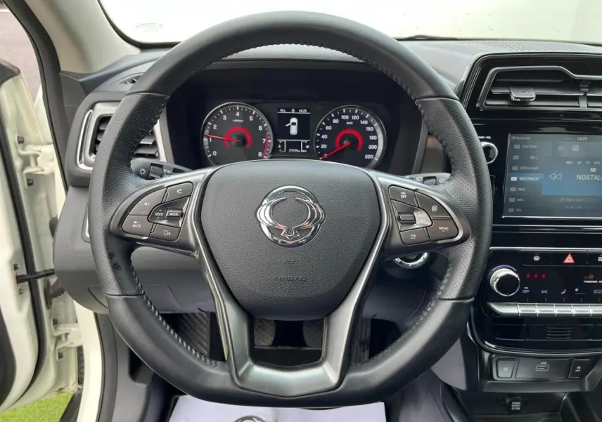 Vue intérieure centrée sur le volant cuir du SsangYong Tivoli blanc 2021 avec tableau de bord et écran tactile 8 pouces.